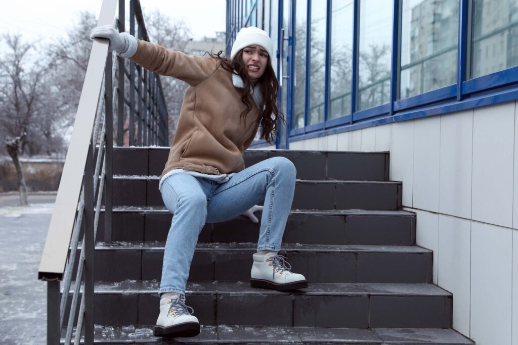 Young woman falls on slippery ice-covered stairs outdoors